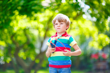 little kid boy shooting wooden slingshot