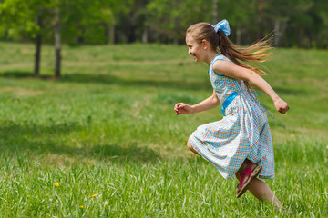 Child girl running at green meadow