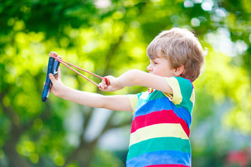 little kid boy shooting wooden slingshot