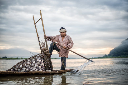 Fisherman on boat in action when fishing of fish trap on Mekong