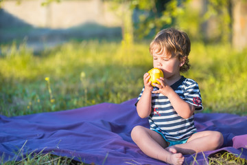 beautiful baby eating an apple outdoors