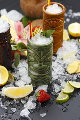 Tropical cocktails served in a tiki style glass and garnished with fruits and ice
