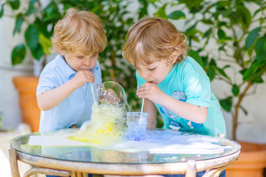Two happy children making experiment with colorful bubbles
