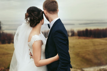 A look from behind on a hugging wedding couple looking at the gr