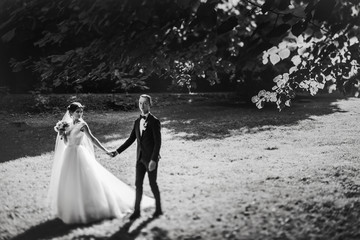 Black and white picture of a wedding couple walking in the garde
