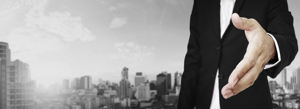Businessman extending hand with panoramic cityscape of business district in the city