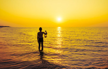 Young boy with lamp at sunrise on the beach