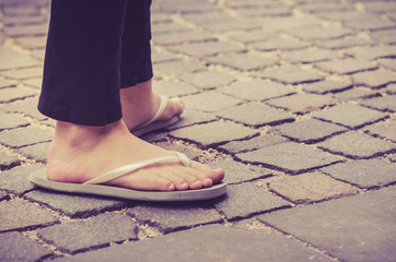 woman in flip Flops standing on a cobblestone street