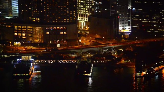 FullHD video - Beautiful and colorful lights of a major city at night, with contemporary highrise buildings, fronted by a busy harbor.