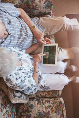 Elderly couple looking images on digital tablet