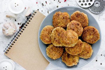 Classic homemade cutlets on white table with notebook