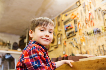 happy little boy with wood plank at workshop