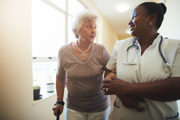 Nurse assisting senior female patient to walk