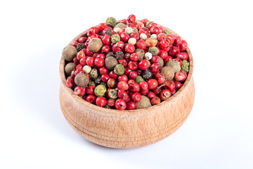 Mix different kind of pepper in a wooden bowl isolated on white background 