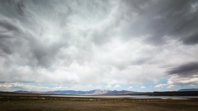 Time-Lapse of clouds moving over a lake, mountain range in the distance.