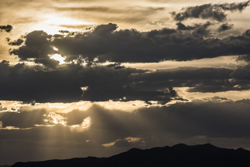 Dramatic yellow cloudy sunset with sun rays and mountains at Bonneville white salt flats, Utah