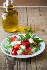 Feta arugula salad with tomatoes on white plate, summer food