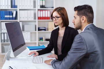kollegen schauen gemeinsam auf computer