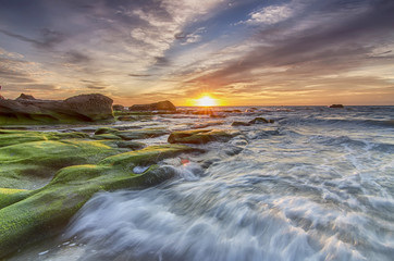 Obraz premium Beautiful sunset decorated with waves and mosses stone