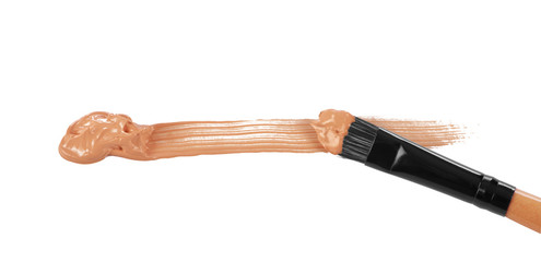 Close-up of makeup brush with smeared liquid foundation on white