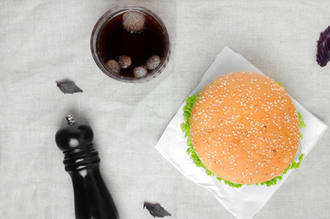 Burger and pepper mill on a table with towel