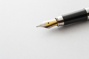 fountain pen lying on the white paper. Texture on paper is viewed.