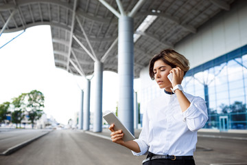 Young successful businesswoman speaking on phone, standing near business centre.