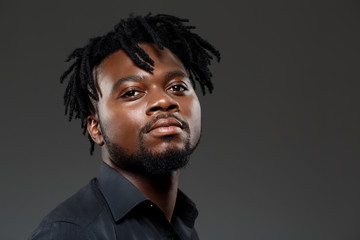Young successful african businessman posing over dark background.