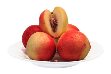 Several nectarine fruits on a plate. One with a cutout. Objects on a white background.