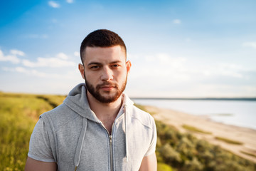 Young sportive man posing in field at sunrise.