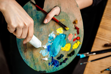 Obraz premium Close up of girl squeezing white oil paint on palette.
