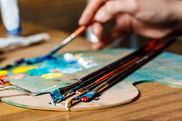 Close up photo of girl mixing oil paints on palette.