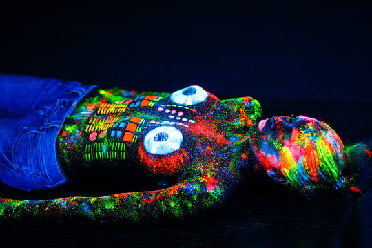 Naked girl painted in UV powder as a DJ panel.