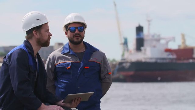 two engineers with laptop communicate in Shipping cargo port