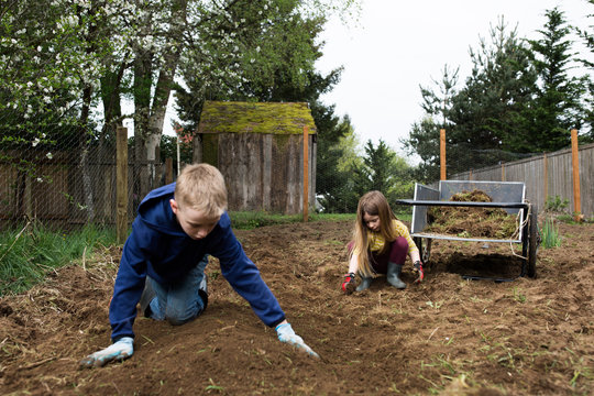 Two children playing with soil in a garden