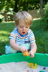 young toddler boy playing in sandbox