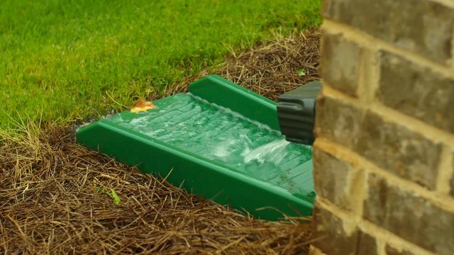 Gutter Down Spout Close Up Rain Water Pouring. rain water pours out of a residential home gutter down spout
