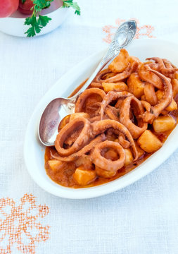 Fish Stew. Stewed squid rings (calamari) in tomato sauce with potatoes(Totani e patate). Rustic Italian food, cooking.