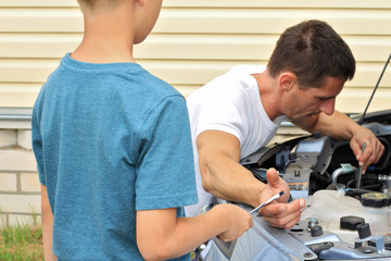 Obraz premium Boy helping Father to repair the car. Family concept