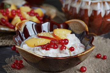 Cottage cheese, red currant and fresh peaches, on wooden table b