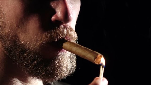 Man in a dark room, smoking a cigar. Black. Slow motion. Close up