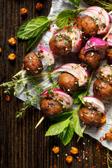 Fototapeta na wymiar Kofta skewers, meatballs and red onion with addition of fresh mint and thyme, delicious oriental cuisine, top view