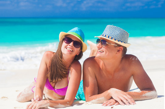 happy couple in sunhats enjoying time at beach