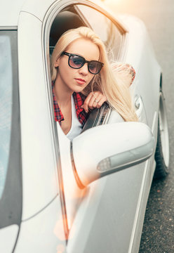 Young woman in sunglasses look out from the car window