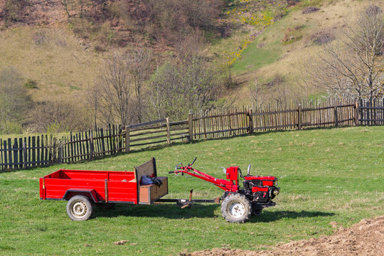 Red behind tractor stands in the farmyard. Agriculture