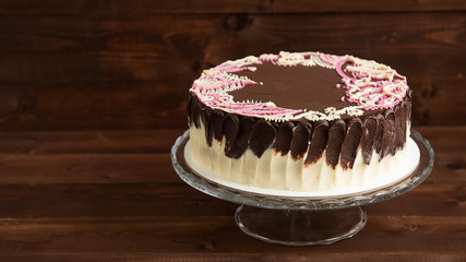 Cake with mehendi patterns on the glass stand. Wooden background.