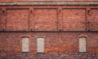 wall of the old factory building of red brick with narrow window