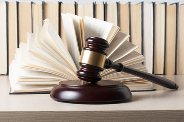 Law concept - Book with wooden judges gavel on table in a courtroom or enforcement office.