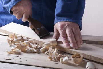 Carpenter working with plane on wooden background at Building Site. Joiner workplace