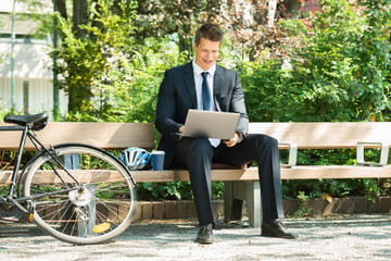 Businessman Sitting On Bench Using Laptop